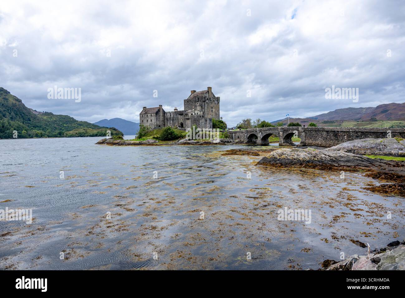 Un château médiéval escarpé se trouve sur un îlot rocheux, entouré d'une eau bleue calme et de collines lointaines. Cette forteresse intemporelle évoque l'histoire, scénographe maritime Banque D'Images