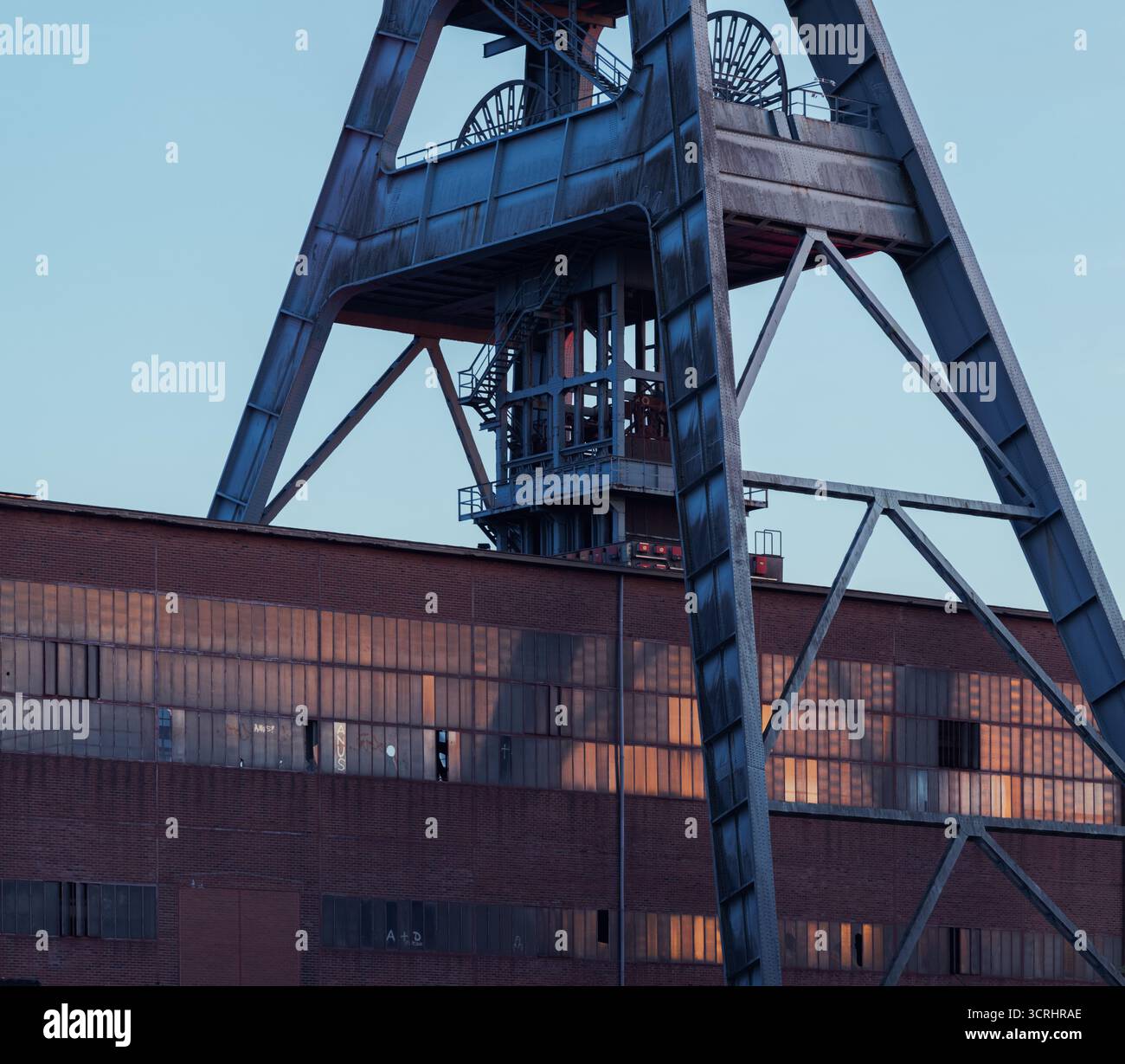 Tour minière industrielle historique au coucher du soleil – monument d'architecture abandonnée avec structure en acier et ciel atmosphérique Banque D'Images