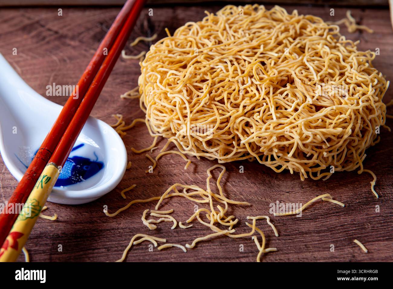 Gros plan de nouilles de blé chinoises fines séchées avec une cuillère en céramique et une paire de baguettes. Banque D'Images