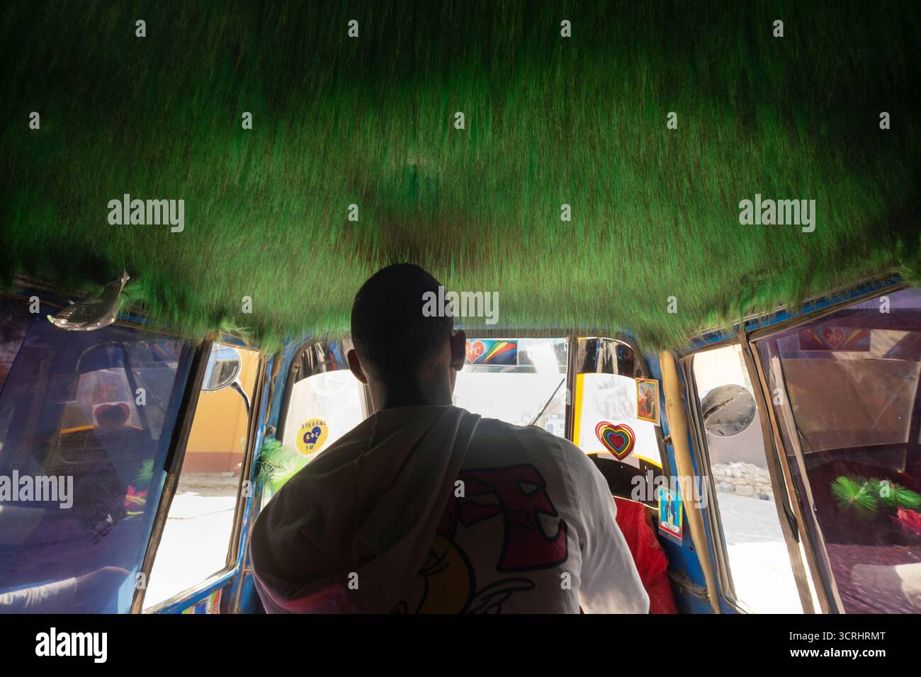Homme conduisant un tuk-tuk avec un intérieur vert fourré unique, Ethiopie Banque D'Images