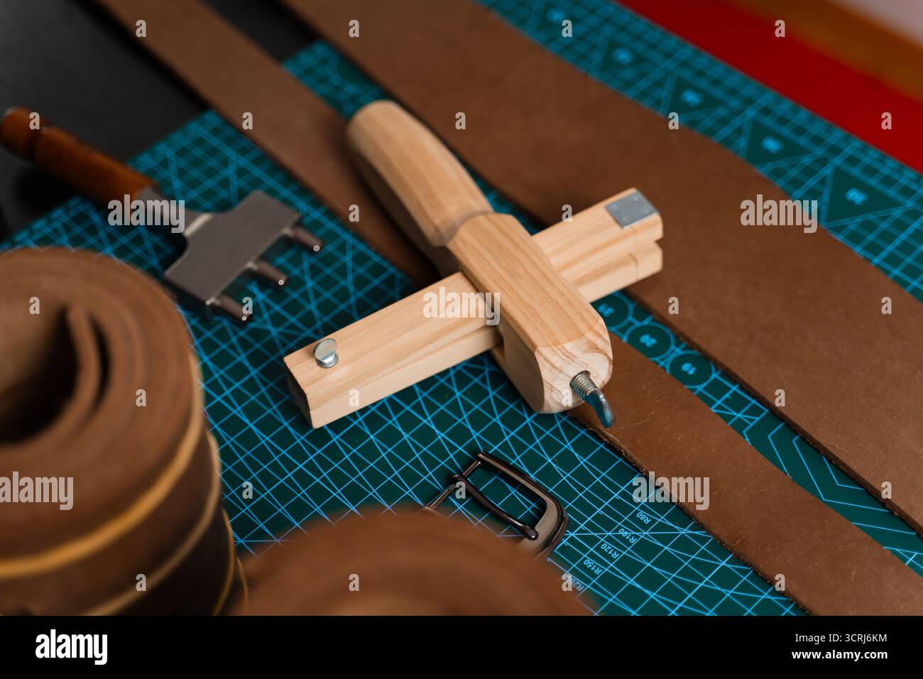 Installation de travail du cuir avec des outils, une boucle et des bandes de cuir disposées soigneusement sur un tapis, prêt pour la fabrication de ceinture. Outils de maroquinerie et fabrication de courroies p Banque D'Images
