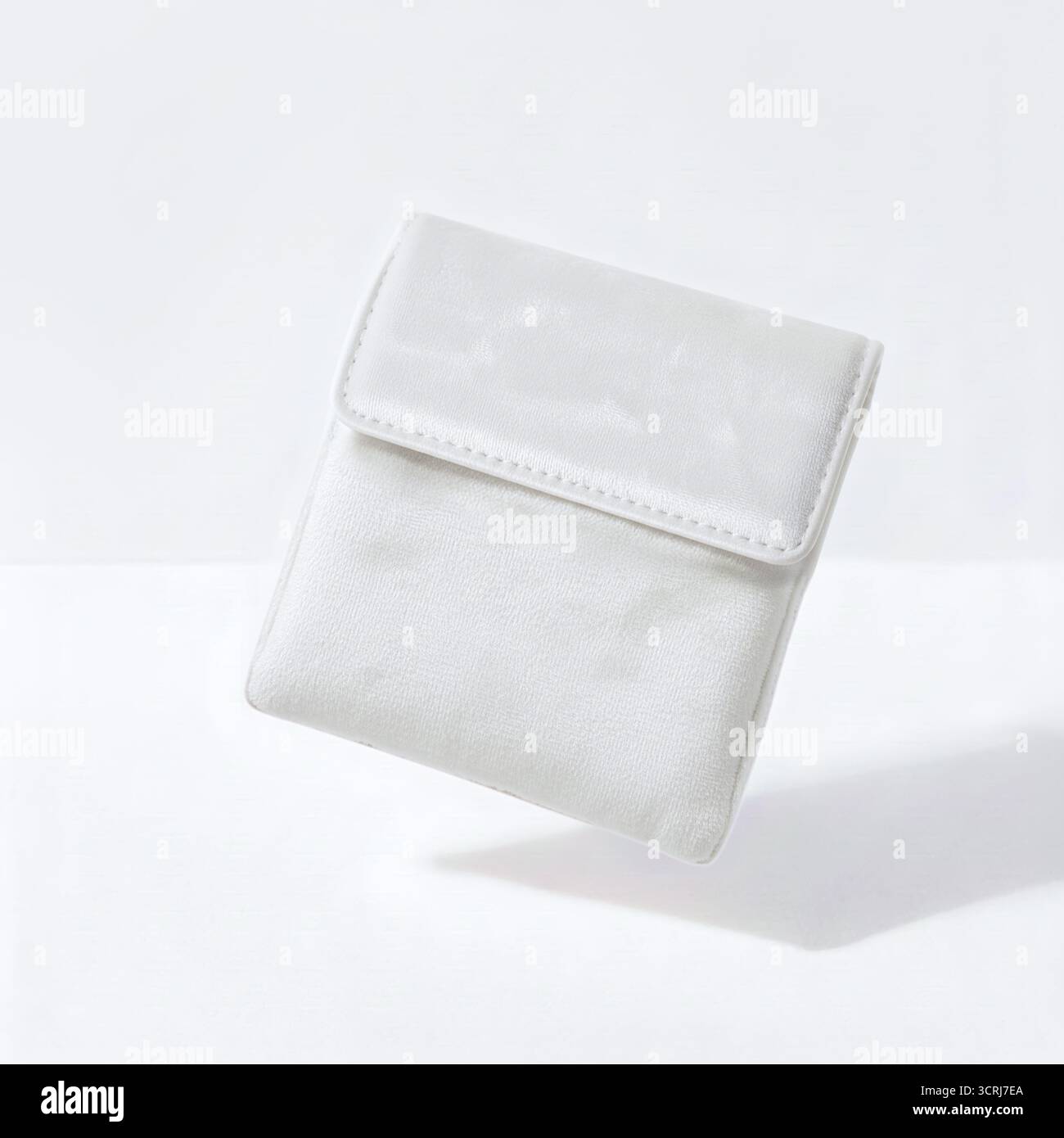 Petit sac en velours blanc flottant sur fond blanc Banque D'Images