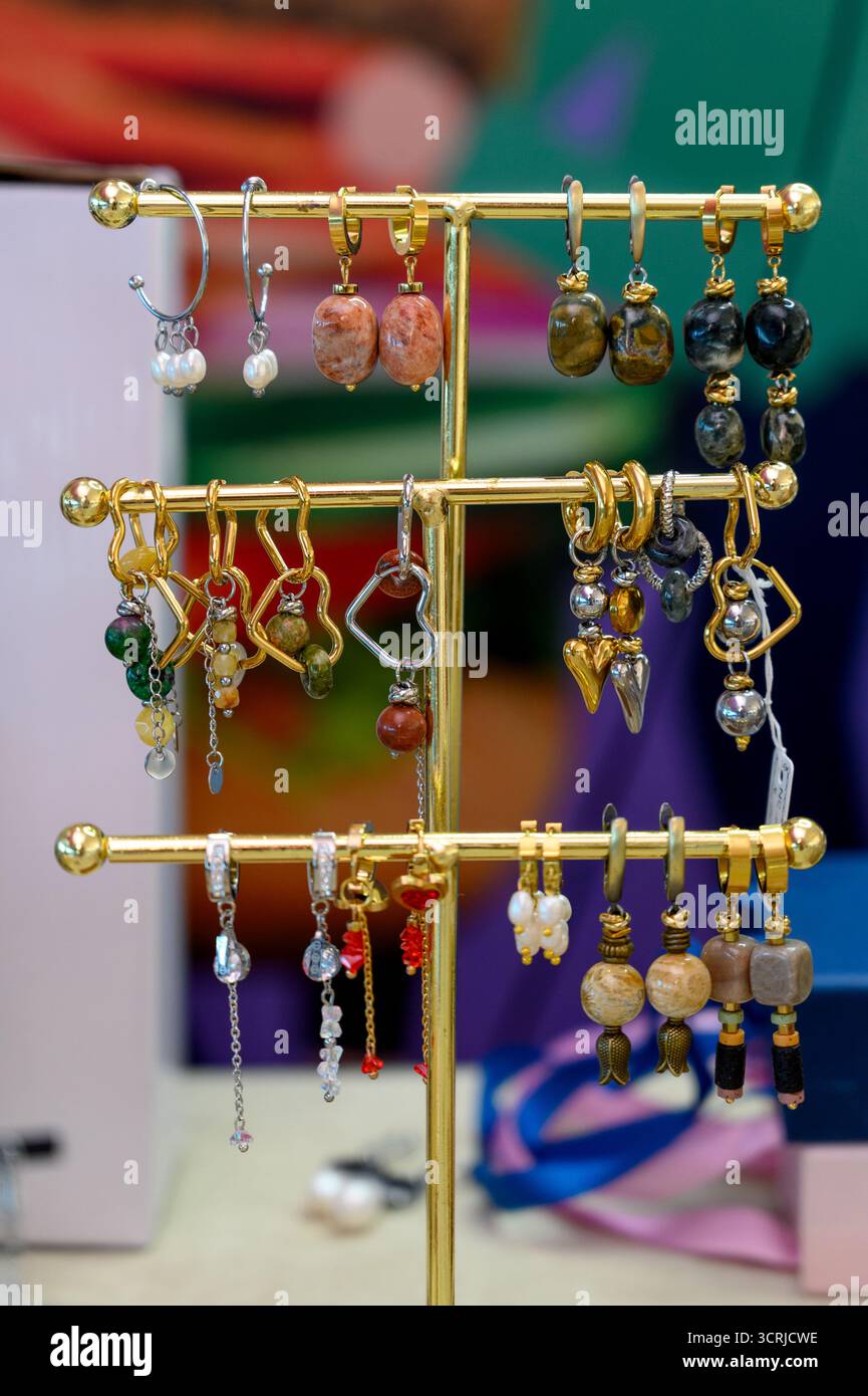 Une collection de boucles d'oreilles fabriquées à la main sur un support de bijoux plaqué or.boucles d'oreilles assorties perlées et en pierre à vendre Banque D'Images