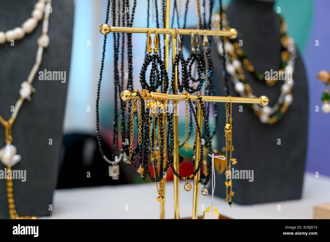 Une collection de boucles d'oreilles fabriquées à la main sur un support de bijoux plaqué or.boucles d'oreilles assorties perlées et en pierre à vendre Banque D'Images