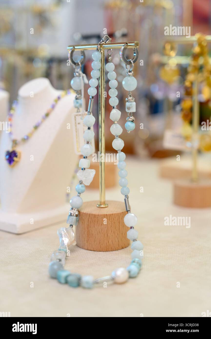 Une collection de boucles d'oreilles fabriquées à la main sur un support de bijoux plaqué or.boucles d'oreilles assorties perlées et en pierre à vendre Banque D'Images
