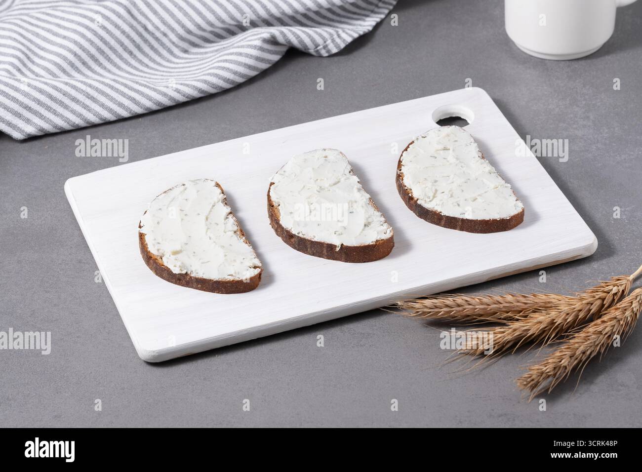 Sandwichs avec fromage à la crème sur une planche à découper blanche Banque D'Images