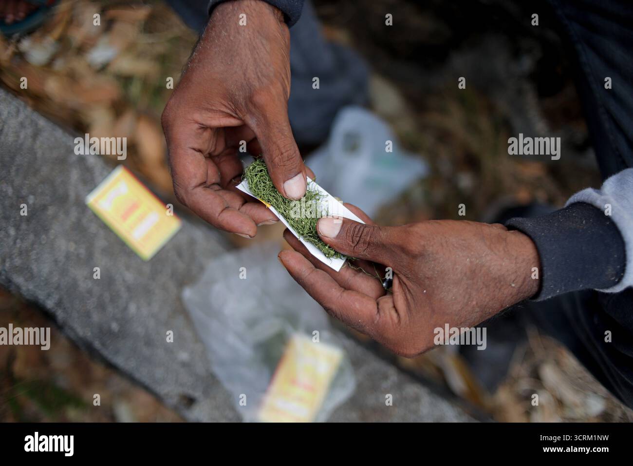 Gros plan de mains roulant une cigarette faite à la main à l'extérieur Banque D'Images Gros plan de mains roulant une cigarette faite à la main à l'extérieur Banque D'Images