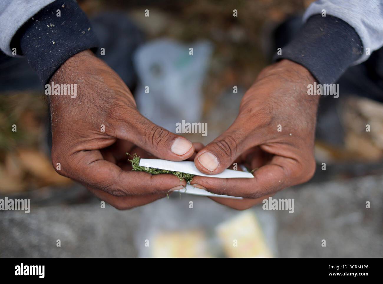 Gros plan de mains roulant une cigarette faite à la main à l'extérieur Banque D'Images Gros plan de mains roulant une cigarette faite à la main à l'extérieur Banque D'Images
