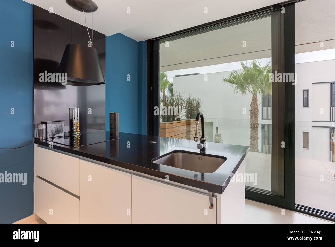 Cuisine moderne avec mur bleu, bar à petit-déjeuner et grandes fenêtres Banque D'Images