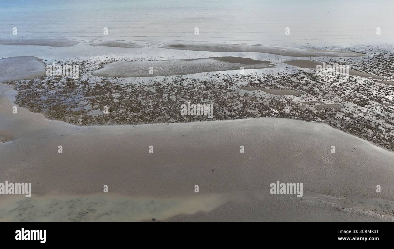 Vue aérienne de la zone intertidale sereine et chatoyante révèle une tapisserie de textures et de couleurs, où les étendues sablonneuses rencontrent des bassins peu profonds, Worthing, Angleterre, Royaume-Uni. Banque D'Images