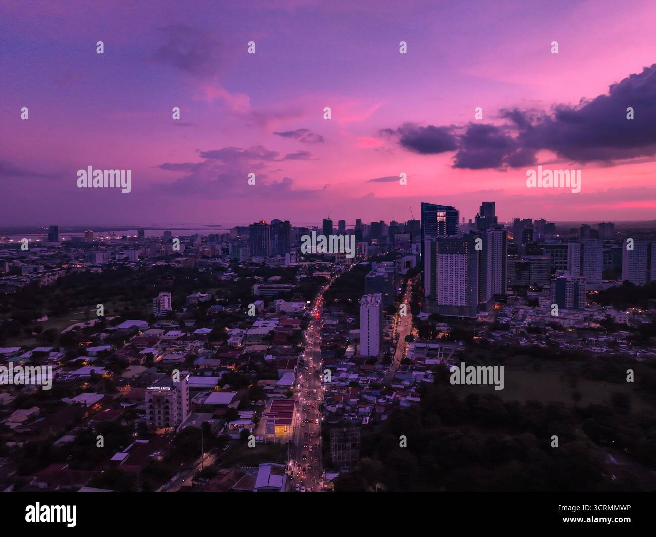 Vue aérienne de l'horizon de la ville baignée dans la lueur chaude du soleil couchant, avec la silhouette des bâtiments debout contre le ciel vibrant, ce Banque D'Images