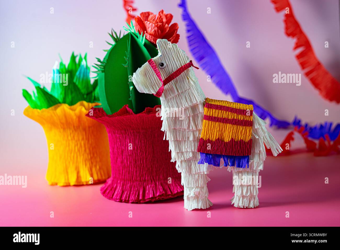Artisanat coloré en papier fait à la main, y compris un lama piñata, un cactus en papier et des faveurs de fête vibrantes, célèbrent la culture mexicaine et l'esprit festif de Banque D'Images