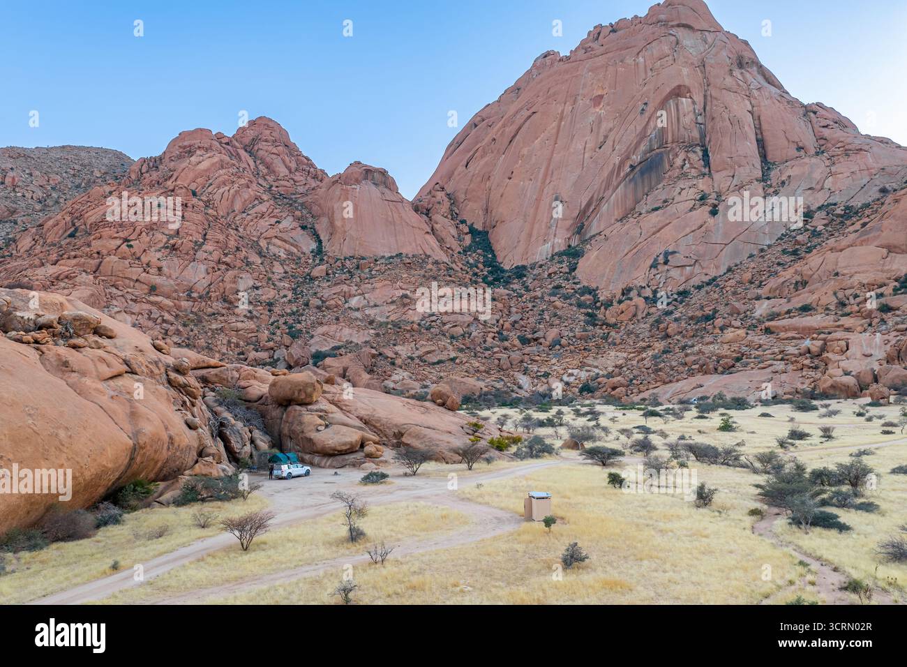 Vue aérienne d'un 4x4 blanc au camping Spitzkoppe, spectaculaire inselberg de granit s'élevant au-dessus de la savane du désert du Namib, région d'Erongo, Namibie. Banque D'Images