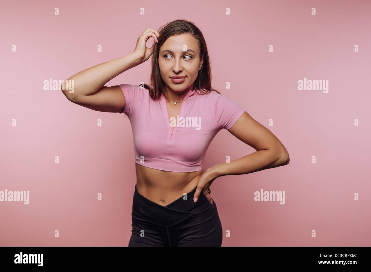 Femme en top rose et pantalon noir avec une expression confuse. Banque D'Images