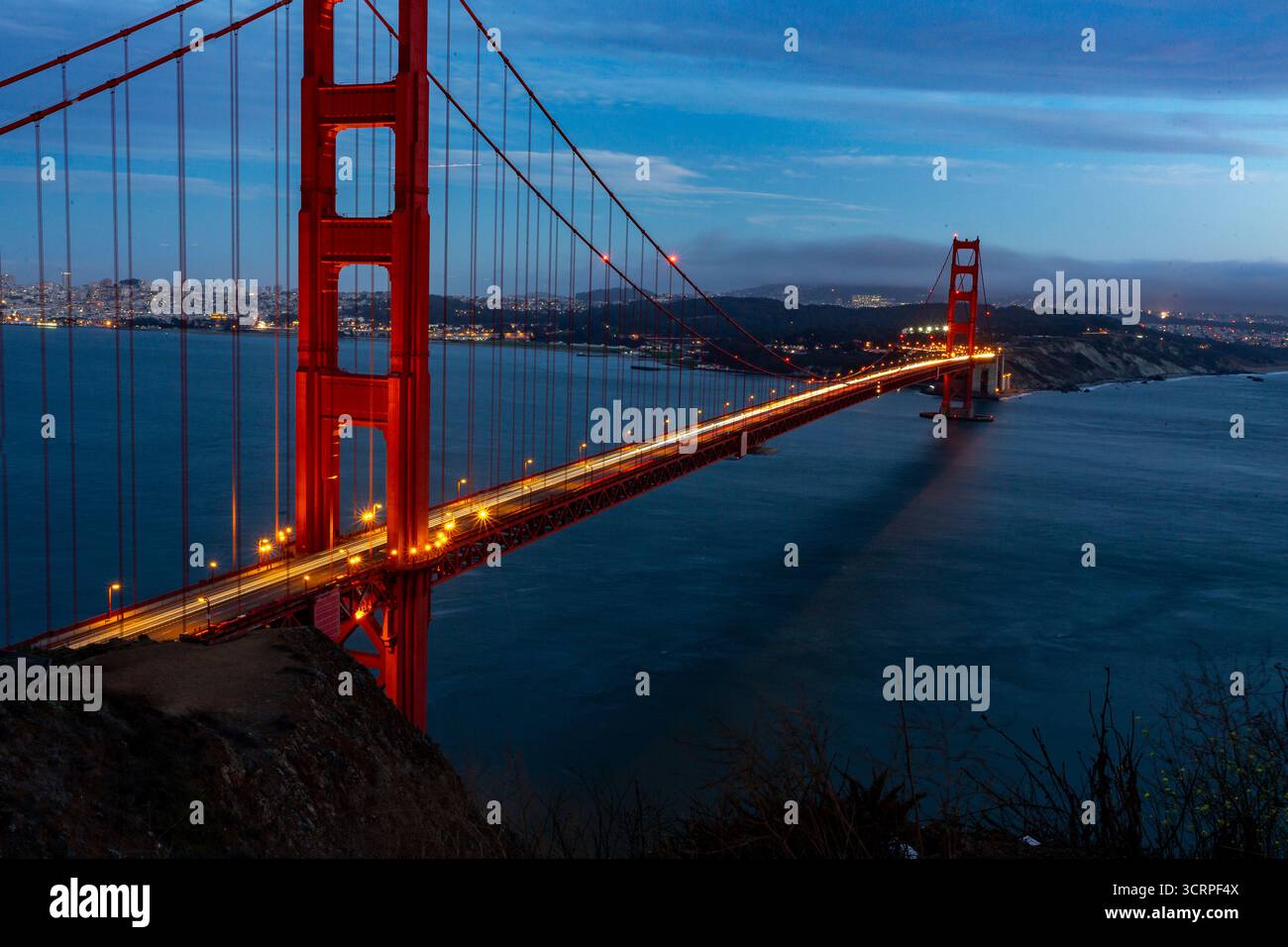 Une photo en exposition longue du Golden Gate Bridge la nuit, montrant les traînées lumineuses des voitures traversant le pont. Banque D'Images