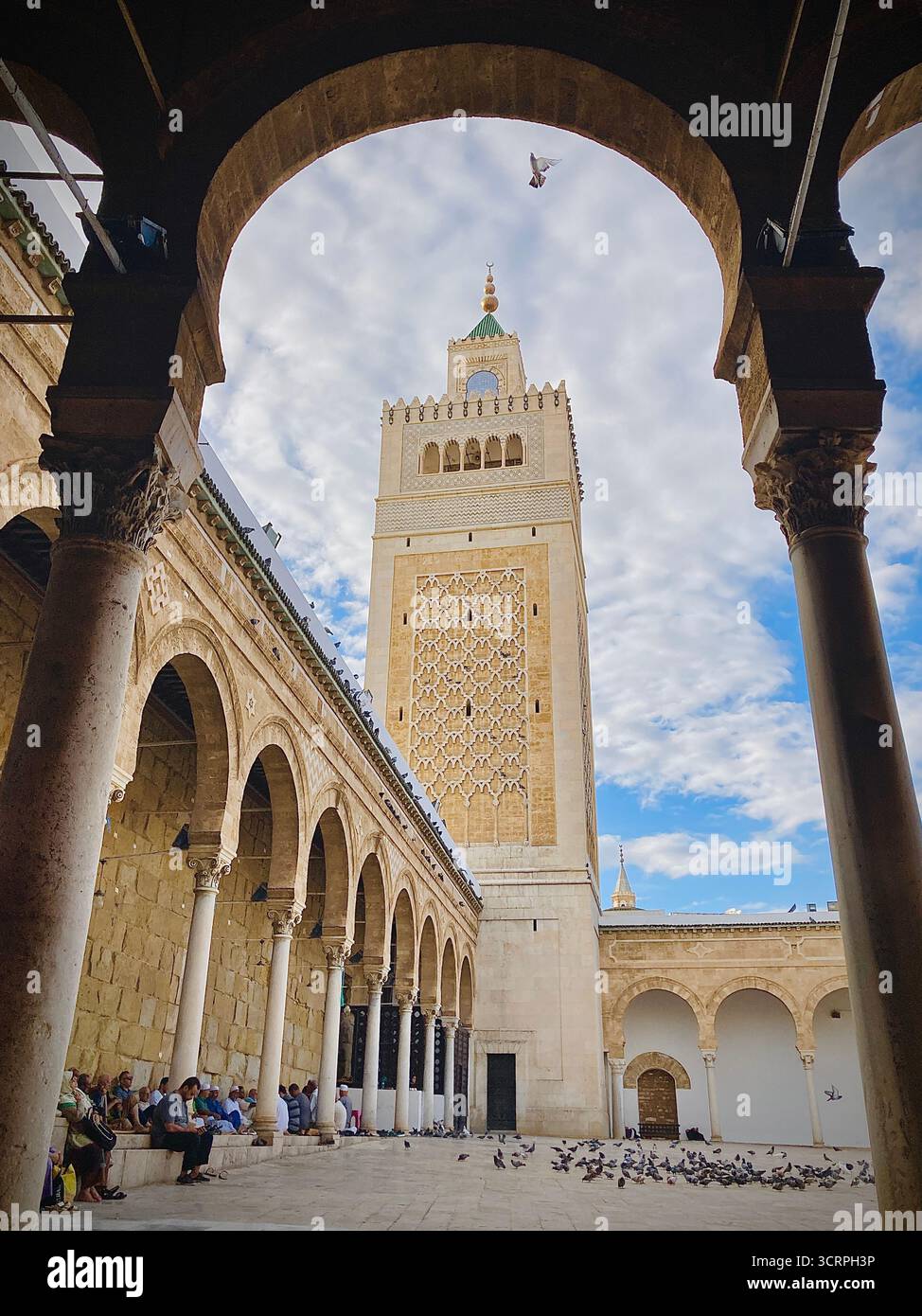 Cour de la mosquée Zitouna à Tunis, Tunisie - colonnades voûtées et minaret encadrés par une arche de pierre. Photographié le 24 septembre 2025. Banque D'Images