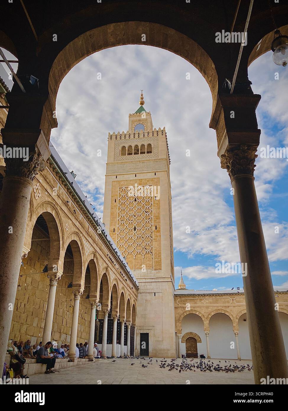 Cour de la mosquée Zitouna à Tunis, Tunisie - colonnades voûtées et minaret encadrés par une arche de pierre. Photographié le 24 septembre 2025. Banque D'Images