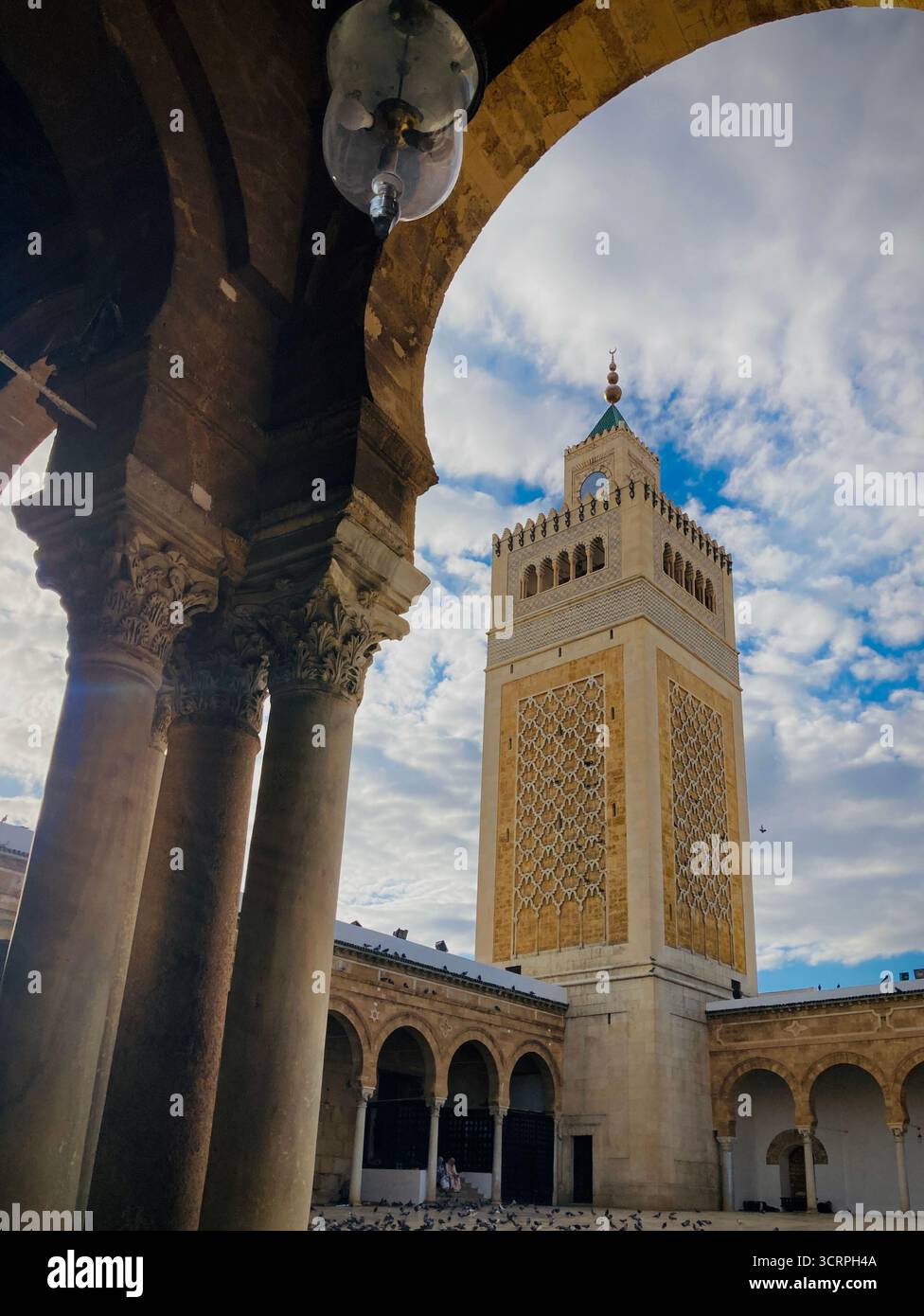 Cour de la mosquée Zitouna à Tunis, Tunisie - colonnades voûtées et minaret encadrés par une arche de pierre. Photographié le 24 septembre 2025. Banque D'Images