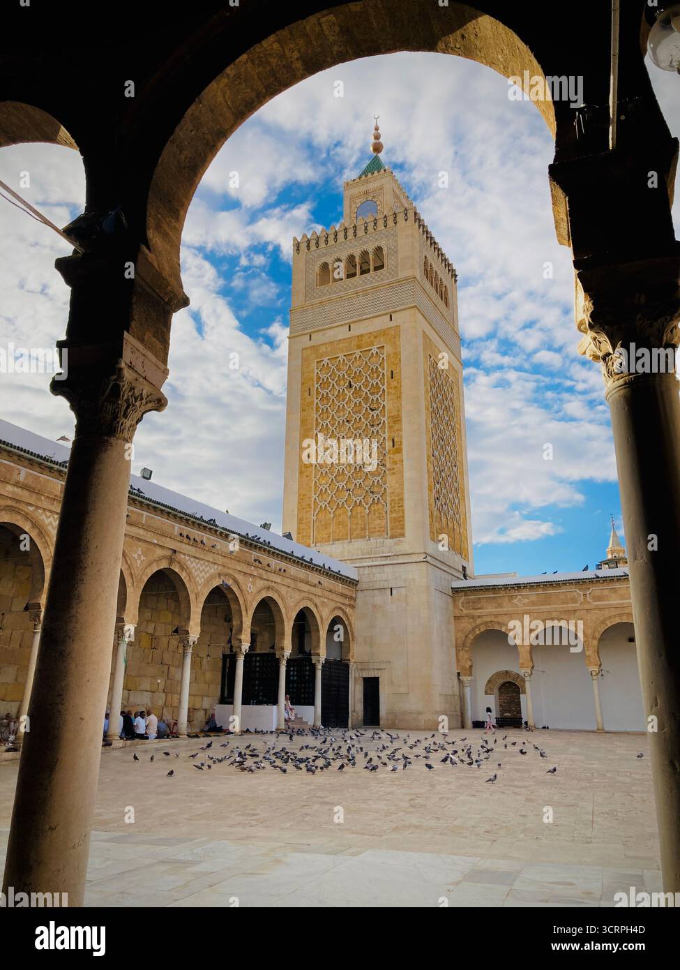 Cour de la mosquée Zitouna à Tunis, Tunisie - colonnades voûtées et minaret encadrés par une arche de pierre. Photographié le 24 septembre 2025. Banque D'Images