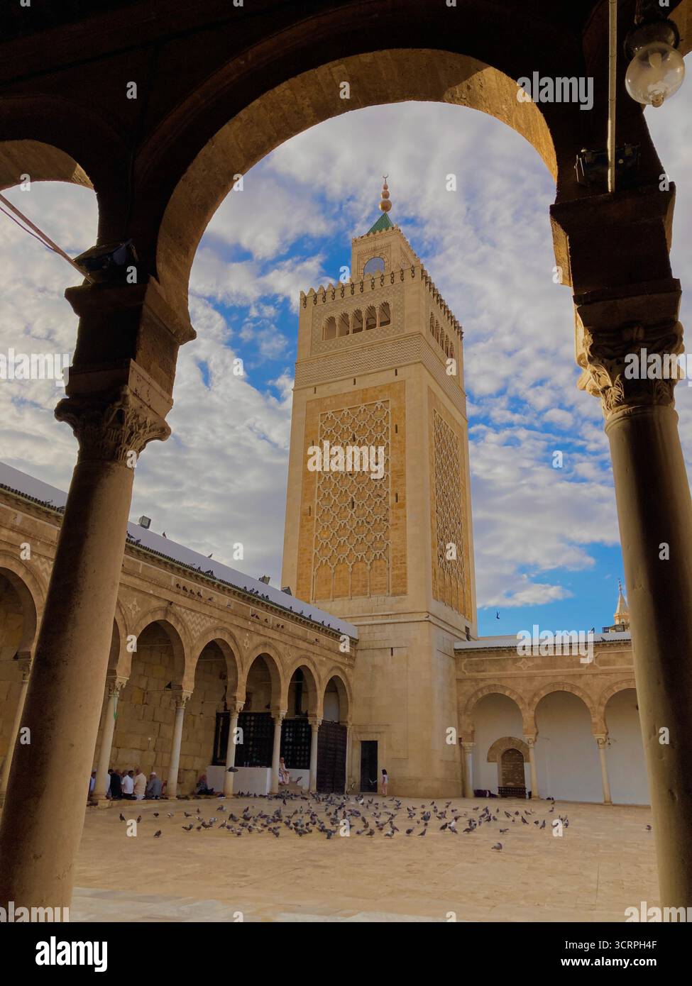Cour de la mosquée Zitouna à Tunis, Tunisie - colonnades voûtées et minaret encadrés par une arche de pierre. Photographié le 24 septembre 2025. Banque D'Images