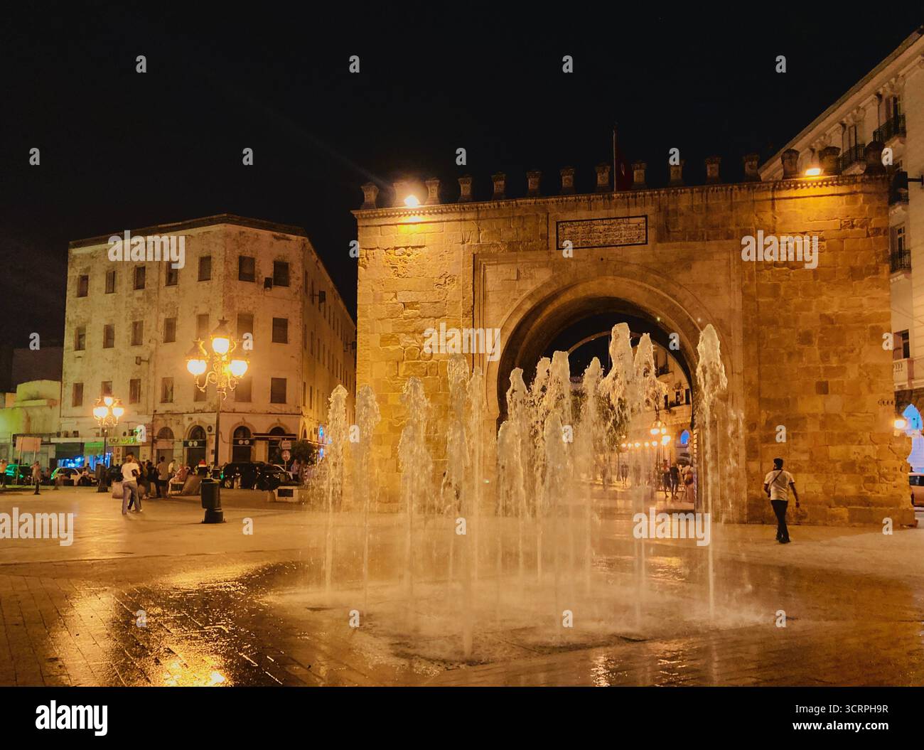 La porte de la ville de Bab El Bhar dans la vieille médina de Tunis, Tunisie, illuminée la nuit par la vie de la fontaine et de la rue. Capturé en septembre 2025. Banque D'Images