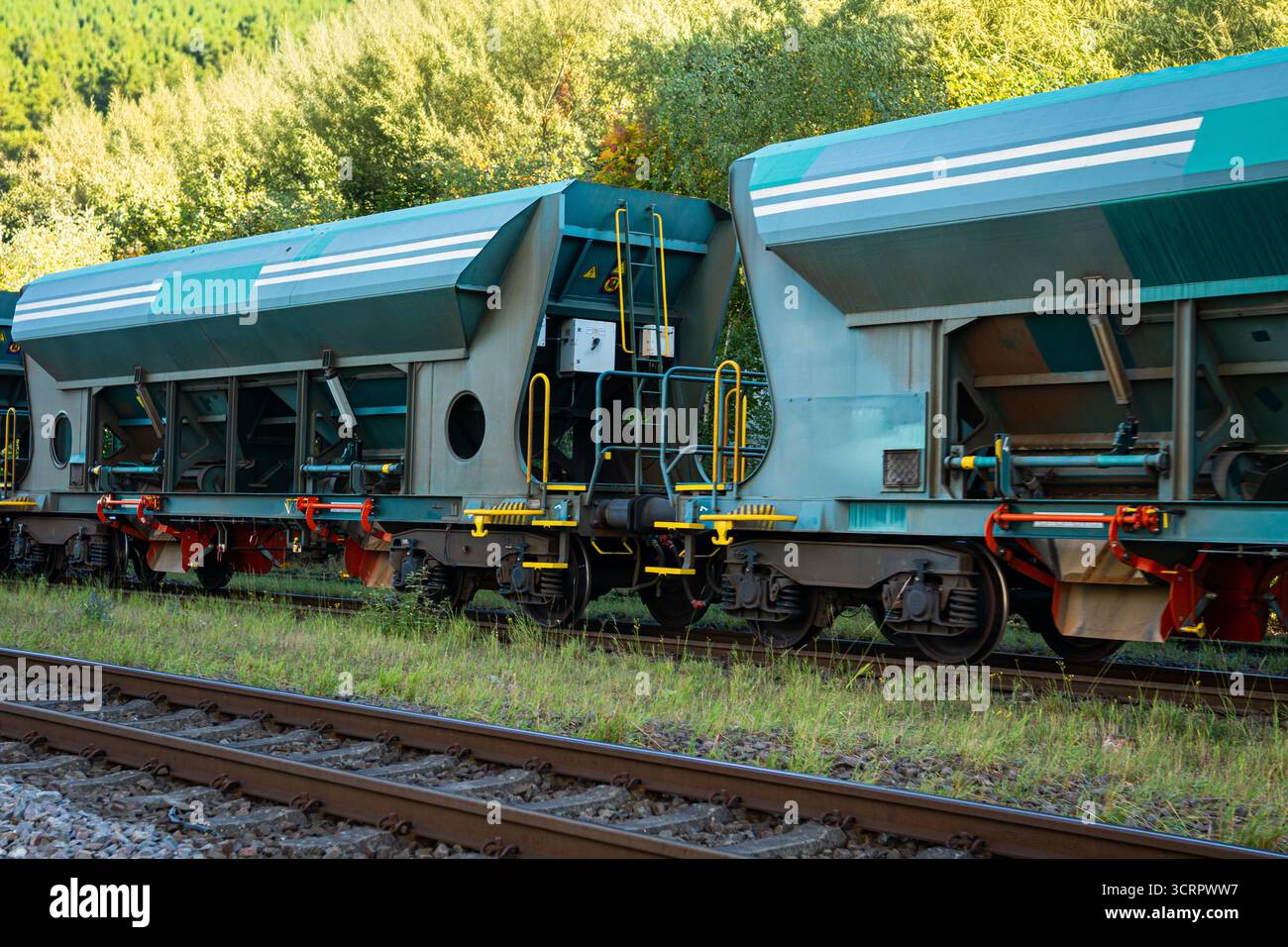 Wagons à trémie de fret modernes debout sur une voie ferrée avec échelles et attelages visibles. Banque D'Images