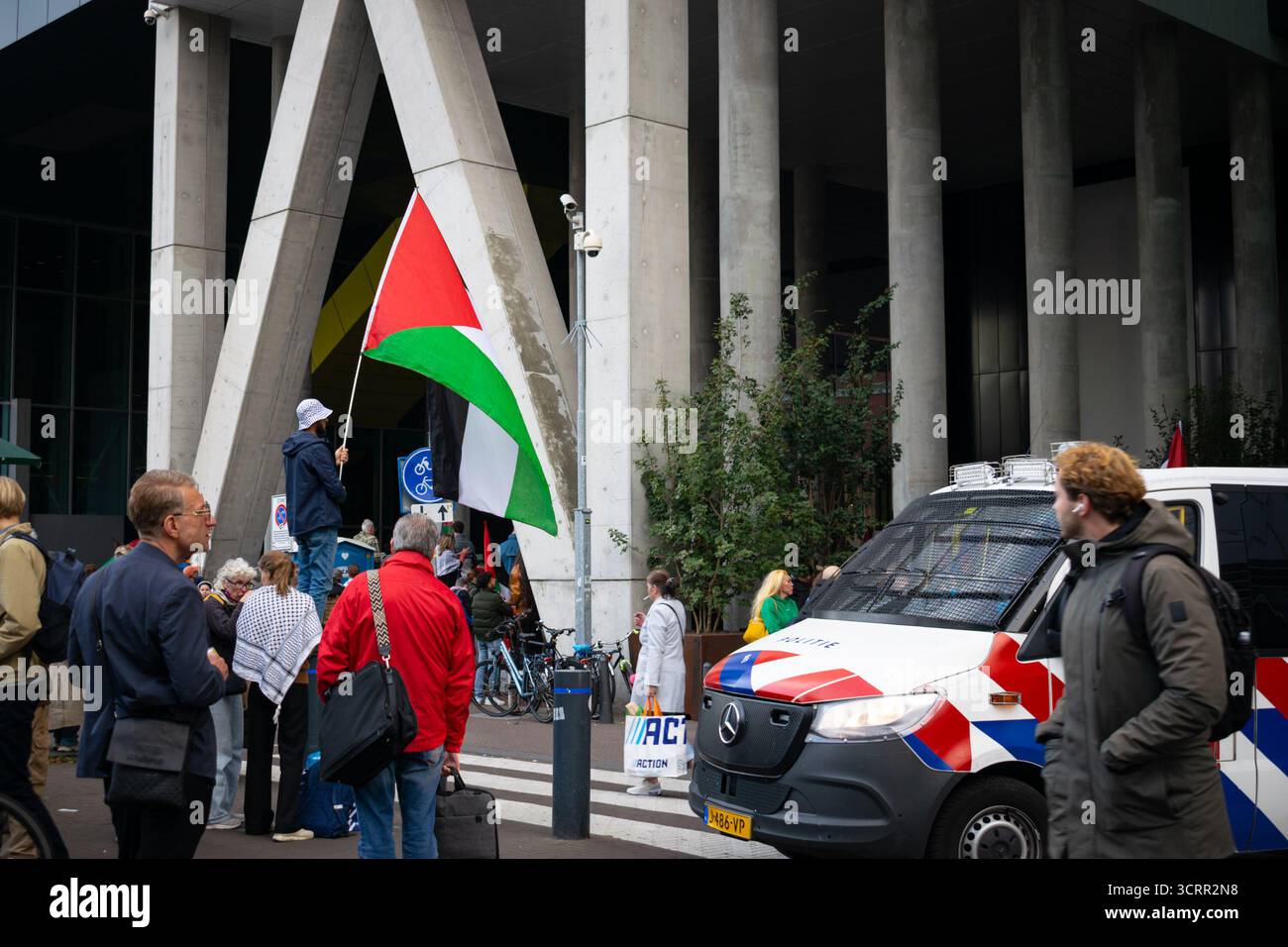 Les gens se sont rassemblés lors d'une manifestation pro-palestinienne à la Haye, avec drapeau palestinien et présence policière près d'un bâtiment gouvernemental moderne. Banque D'Images