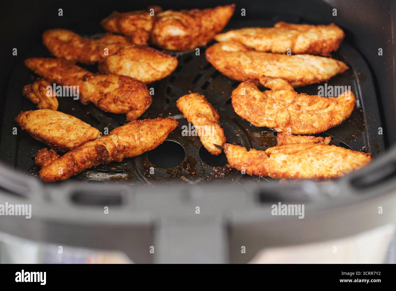 Filets de poulet croustillants cuits dans une friteuse à air. Préparation de repas maison avec filets panés dorés. Alternative saine à la friture. Banque D'Images