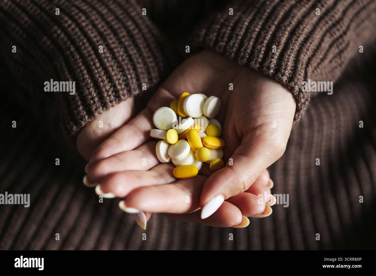 Femme tenant des pilules colorées et des capsules dans les mains. Concept de prendre des médicaments, des vitamines et des suppléments. Soins de santé et routine de bien-être à domicile. Banque D'Images
