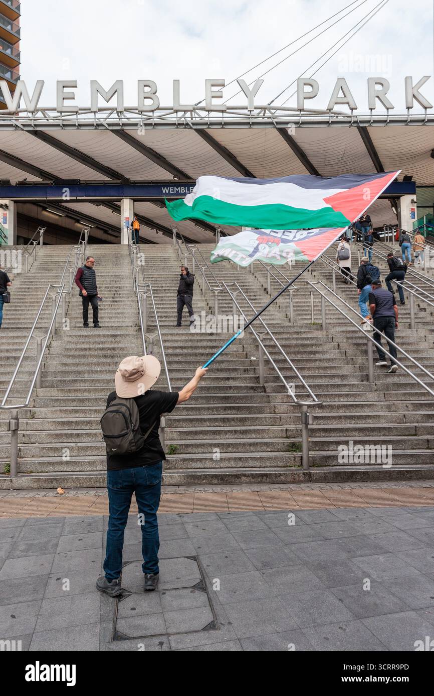 Londres, Royaume-Uni. 2 octobre 2025. Un militant pro-palestinien tient un drapeau palestinien devant la station de Wembley Park avant une marche vers le stade de Wembley pour exiger que l'Association de football publie une déclaration publique demandant que l'Association israélienne de football (IFA) soit suspendue de toute participation aux tournois de l'UEFA et de la FIFA. La pression monte pour que les équipes israéliennes soient suspendues depuis qu’une commission d’enquête de l’ONU a conclu qu’Israël avait commis un génocide contre les Palestiniens à Gaza. Crédit : Mark Kerrison/Alamy Live News Banque D'Images