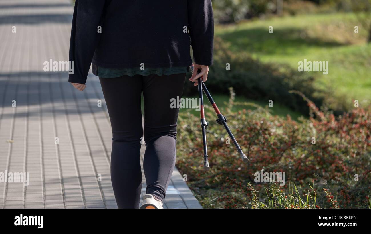 Personne marchant sur un chemin pavé tenant des bâtons de marche nordique Banque D'Images