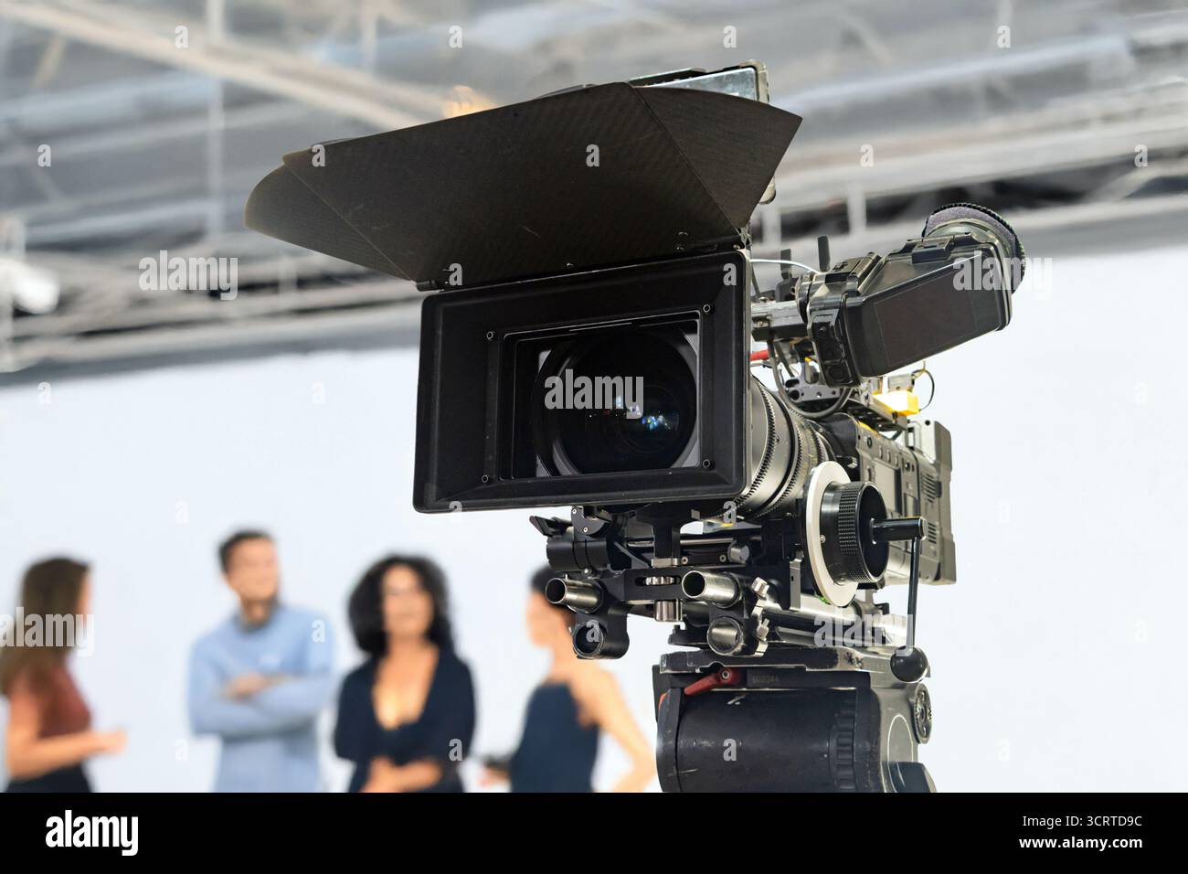 Une caméra de film professionnelle dans un environnement de studio avec un groupe de personnes sur un fond Banque D'Images