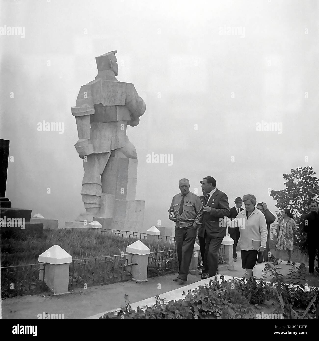 Une photographie d'archives en noir et blanc des années 1960 montre une délégation officielle visitant le colossal Monument à Artem à Sviatohirsk, en RSS d'Ukraine. Le groupe, comprenant des représentants du parti et des anciens combattants décorés, se promène à la base de la statue géante. Conçu par Ivan Kavaleridze, le monument est un chef-d'œuvre mondialement connu de l'art soviétique, exécuté dans un style cubiste/constructiviste unique. Cette image capture un pèlerinage officiel à l'un des monuments idéologiques les plus importants de la région du Donbass et de toute l'URSS Banque D'Images