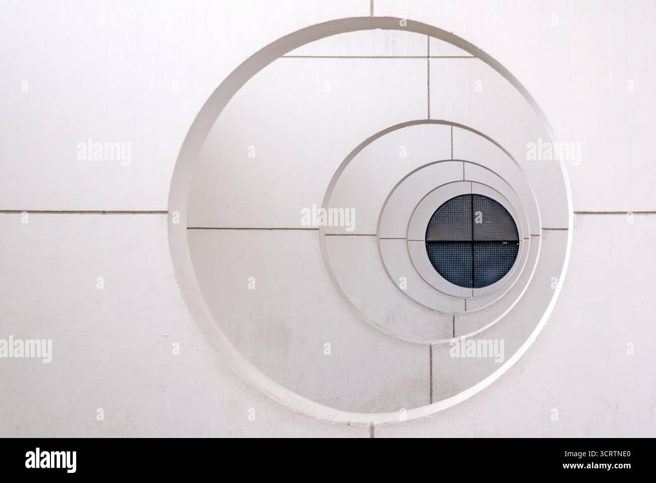 Circulaire symétrique avec anneaux blancs concentriques sur mur en mosaïque. Détail d'architecture géométrique minimaliste, élément de conception moderne, motif abstrait Banque D'Images