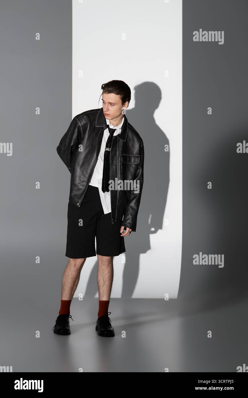 Un adolescent confiant dans une veste en cuir et un short incarne la culture de la jeunesse. Banque D'Images