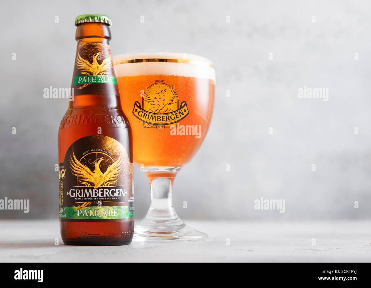 LONDRES, Royaume-Uni - 10 AVRIL 2025 : bouteille et verre original de bière Grimbergen pale ALE sur table lumineuse. Banque D'Images