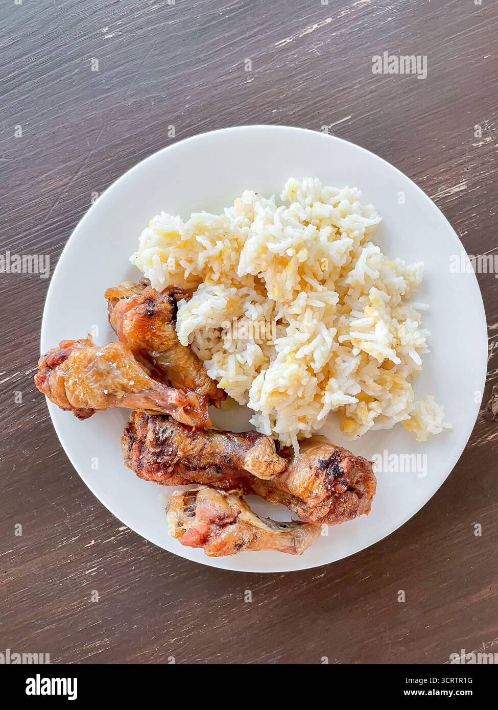 Des ailes de poulet croustillantes cuites au four sont servies avec du riz moelleux et des lentilles cuites sur l'assiette. Porte-plats sur une table en bois rustique Banque D'Images