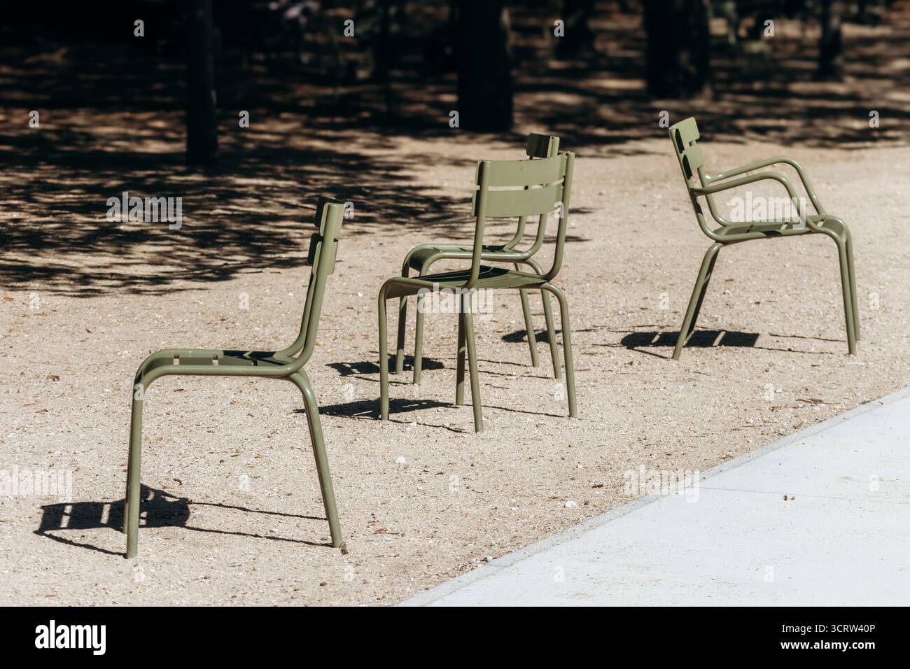 Des chaises emblématiques en métal vert se tiennent vides sur un chemin de gravier ensoleillé dans le célèbre parc de la ville - jardin du Luxembourg, Paris, France Banque D'Images