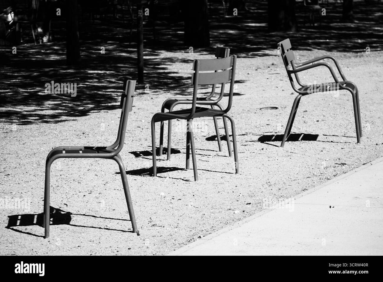 Des chaises emblématiques en métal vert se tiennent vides sur un chemin de gravier ensoleillé dans le célèbre parc de la ville - jardin du Luxembourg, Paris, France Banque D'Images