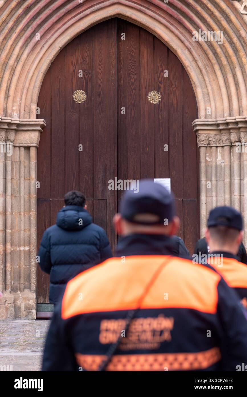 Un officier de la protection civile monte la garde devant l'église Santa Marina en attendant le cortège final de Pâques à Séville, en Espagne. Banque D'Images