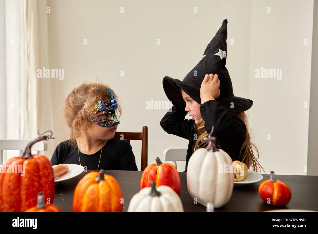 Deux enfants heureux dans des costumes d'Halloween colorés profitent d'une atmosphère vibrante remplie de citrouilles et de joie Banque D'Images Deux enfants heureux dans des costumes d'Halloween colorés profitent d'une atmosphère vibrante remplie de citrouilles et de joie Banque D'Images