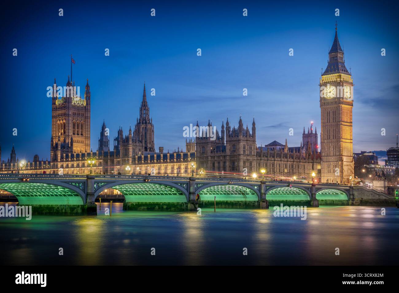 Vue sur Big Ben et les chambres du Parlement à Londres pendant l'heure bleue, avec Westminster Bridge au premier plan et réflexions sur la Tamise R. Banque D'Images