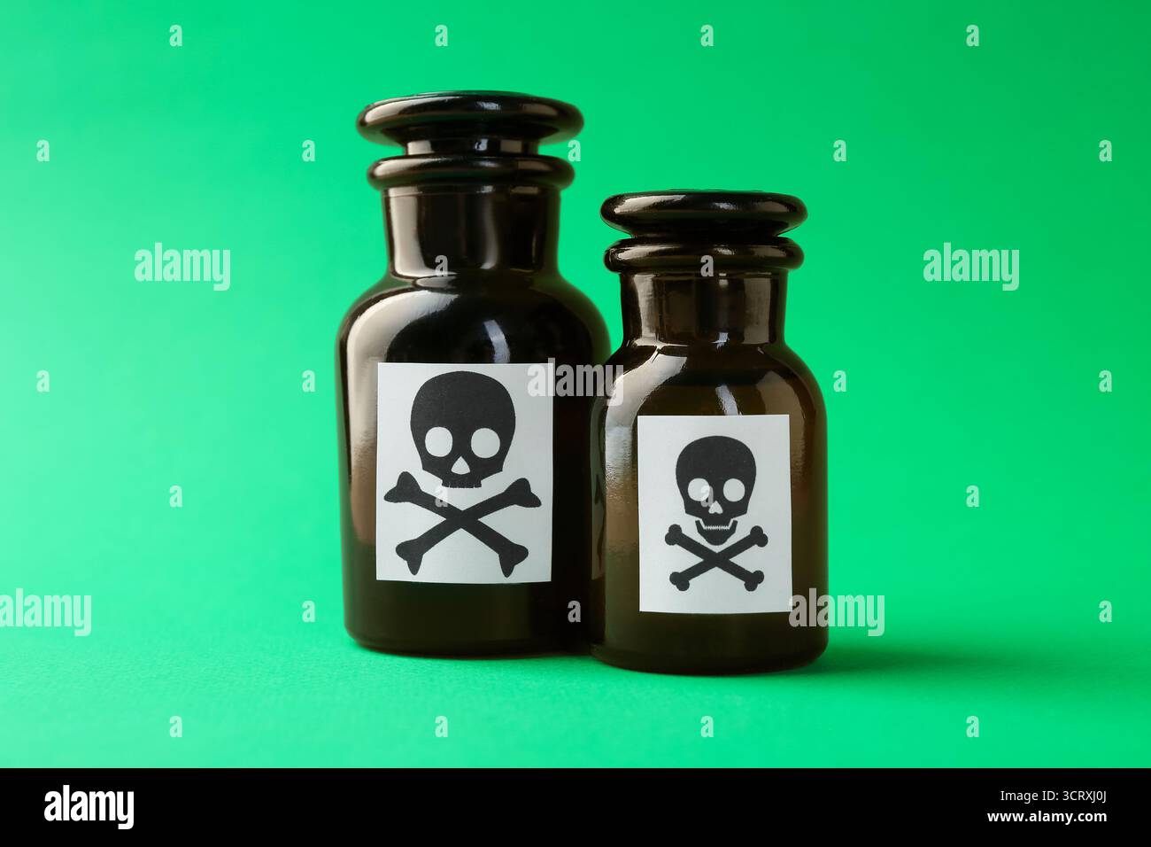 Bouteilles de poison avec des signes d'avertissement sur fond vert, gros plan Banque D'Images