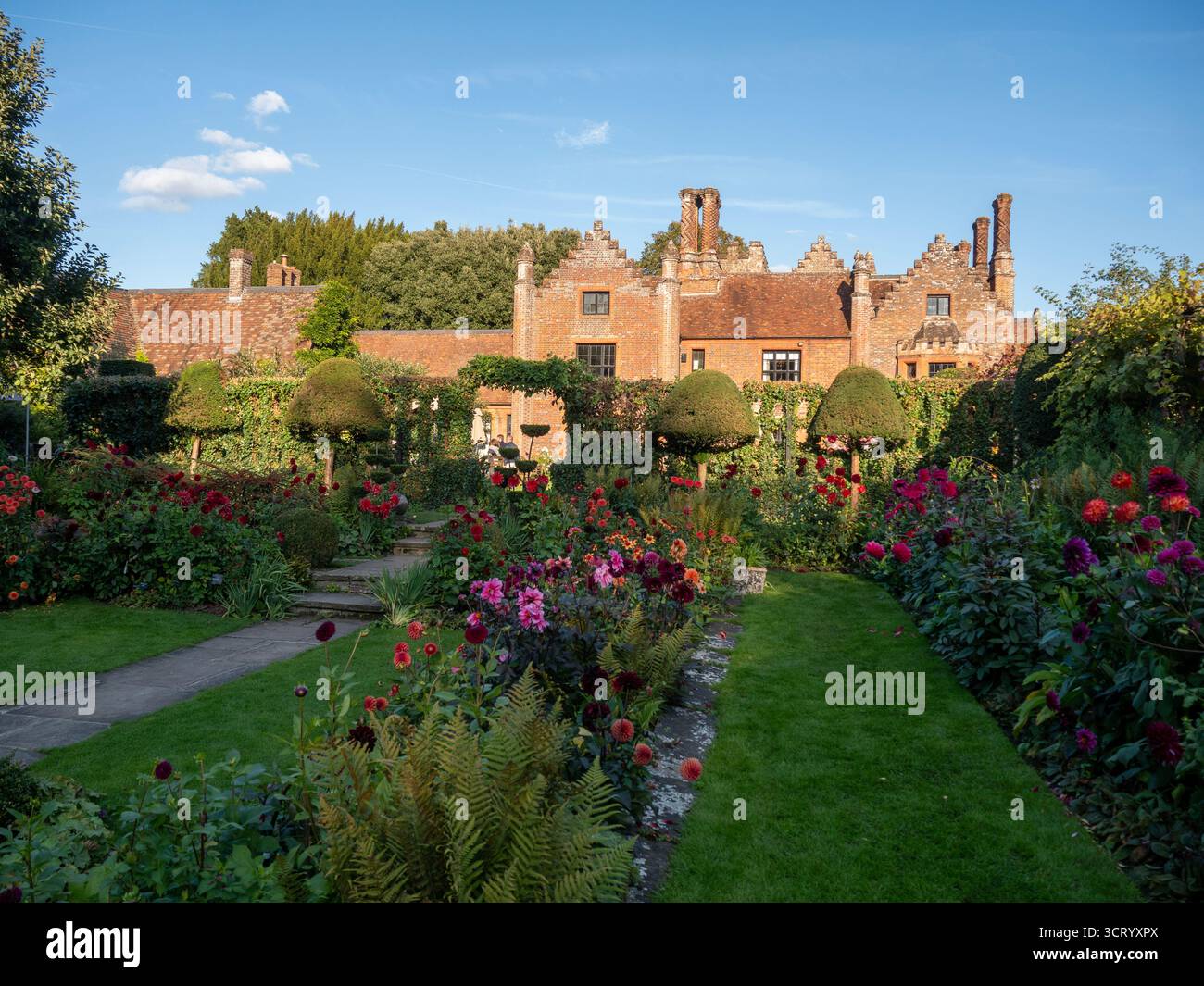 Chenies Manor Sunken Garden sur un beau septembre après-midi.Dahlias en pleine floraison.ombres rampantes sur la pelouse ; manoir Tudor contre le ciel bleu. Banque D'Images