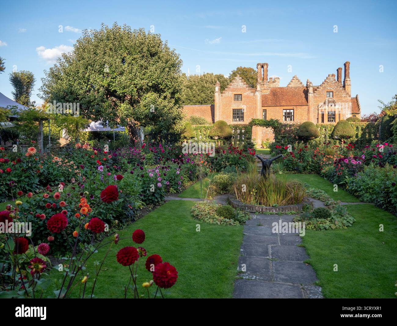 Chenies Manor Sunken Garden sur un beau septembre après-midi.Dahlias en pleine floraison.ombres rampantes sur la pelouse ; manoir Tudor contre le ciel bleu. Banque D'Images