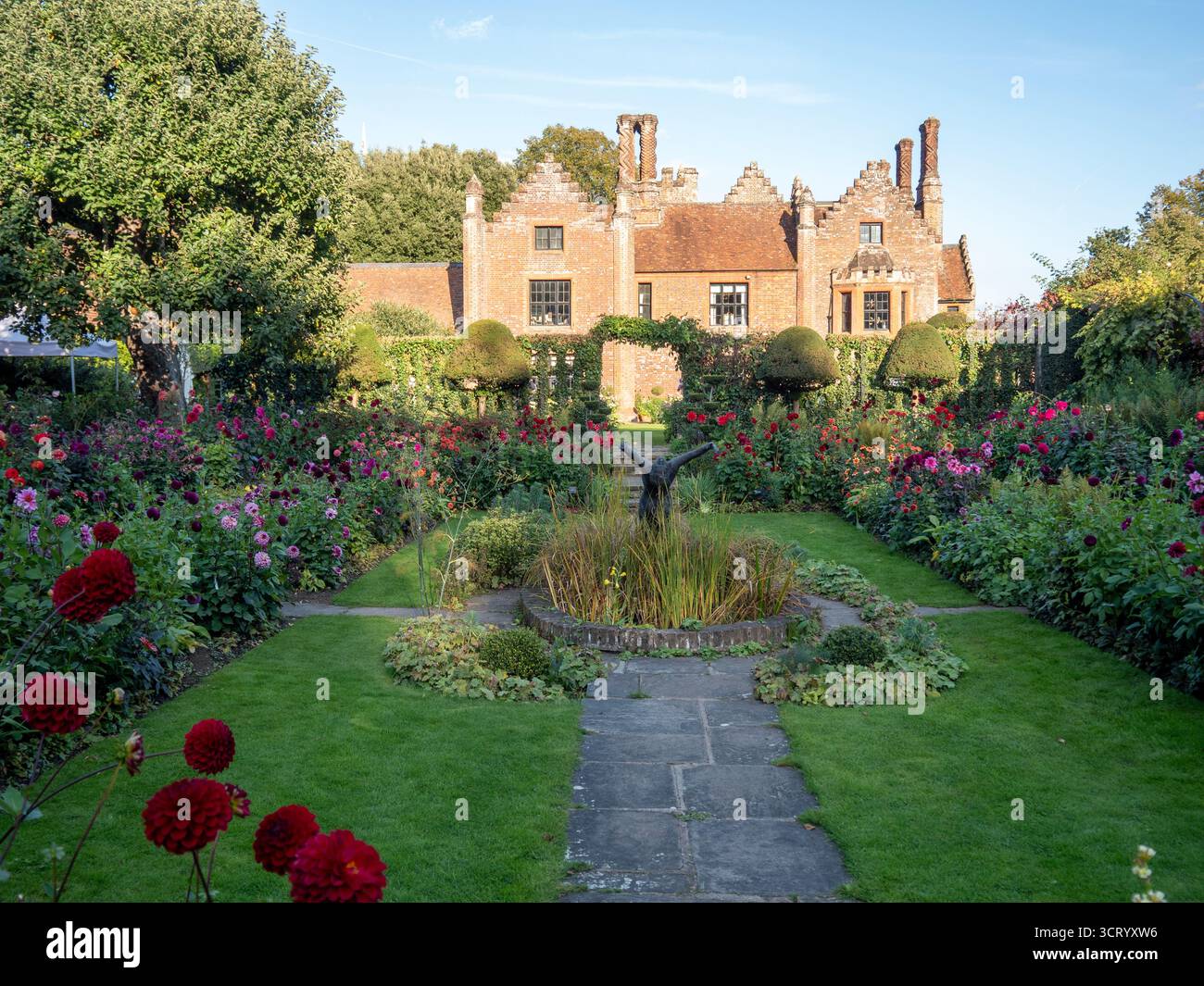 Chenies Manor Sunken Garden sur un beau septembre après-midi.Dahlias en pleine floraison.ombres rampantes sur la pelouse ; manoir Tudor contre le ciel bleu. Banque D'Images