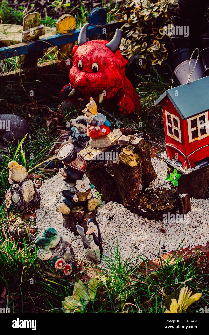 Scène de jardin fantaisiste à Nikiszowiec, Katowice, Pologne, avec de petites figurines animales, une figure de diable rouge et une petite maison rouge sur gravier blanc. Banque D'Images