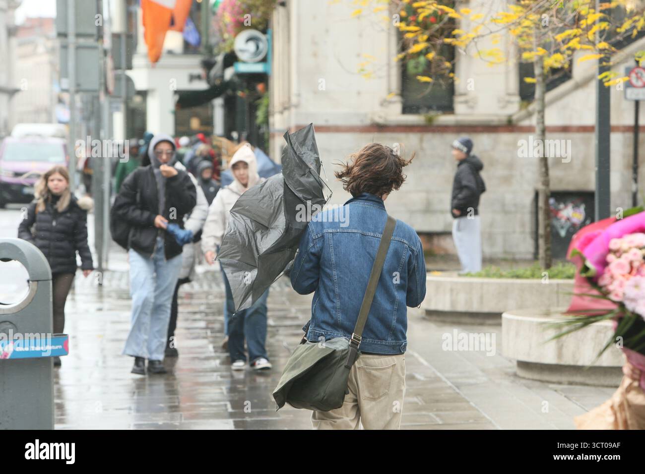Dublin, Irlande - 03 octobre 2025 - Un homme lutte avec un parapluie retourné à l'envers dans le vent sur Dame Street dans le centre-ville de Dublin par une journée humide et bruyante pendant la tempête Amy Banque D'Images