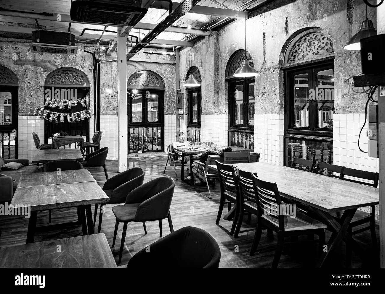 Photo en noir et blanc d'un intérieur de restaurant rustique vide avec des ballons de joyeux anniversaire sur un restaurant mural en bois à Ipoh Malaisie - Image de stock capturée avec un smartphone