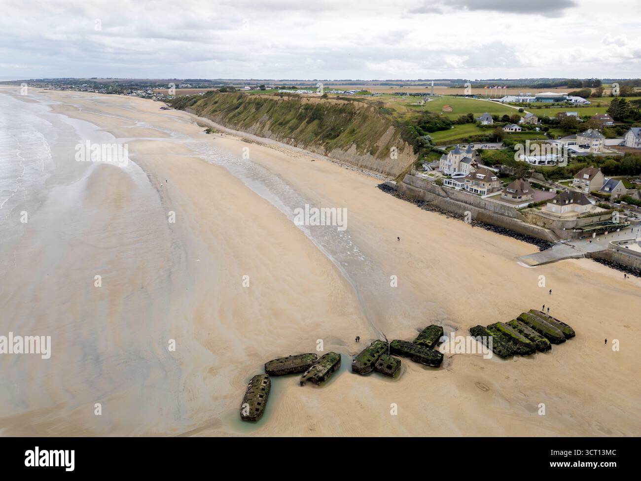 Les gens marchent à marée basse autour des vestiges de Mulberry Harbour sur la plage d'Arromanches-les-bains, Normandie, France Banque D'Images
